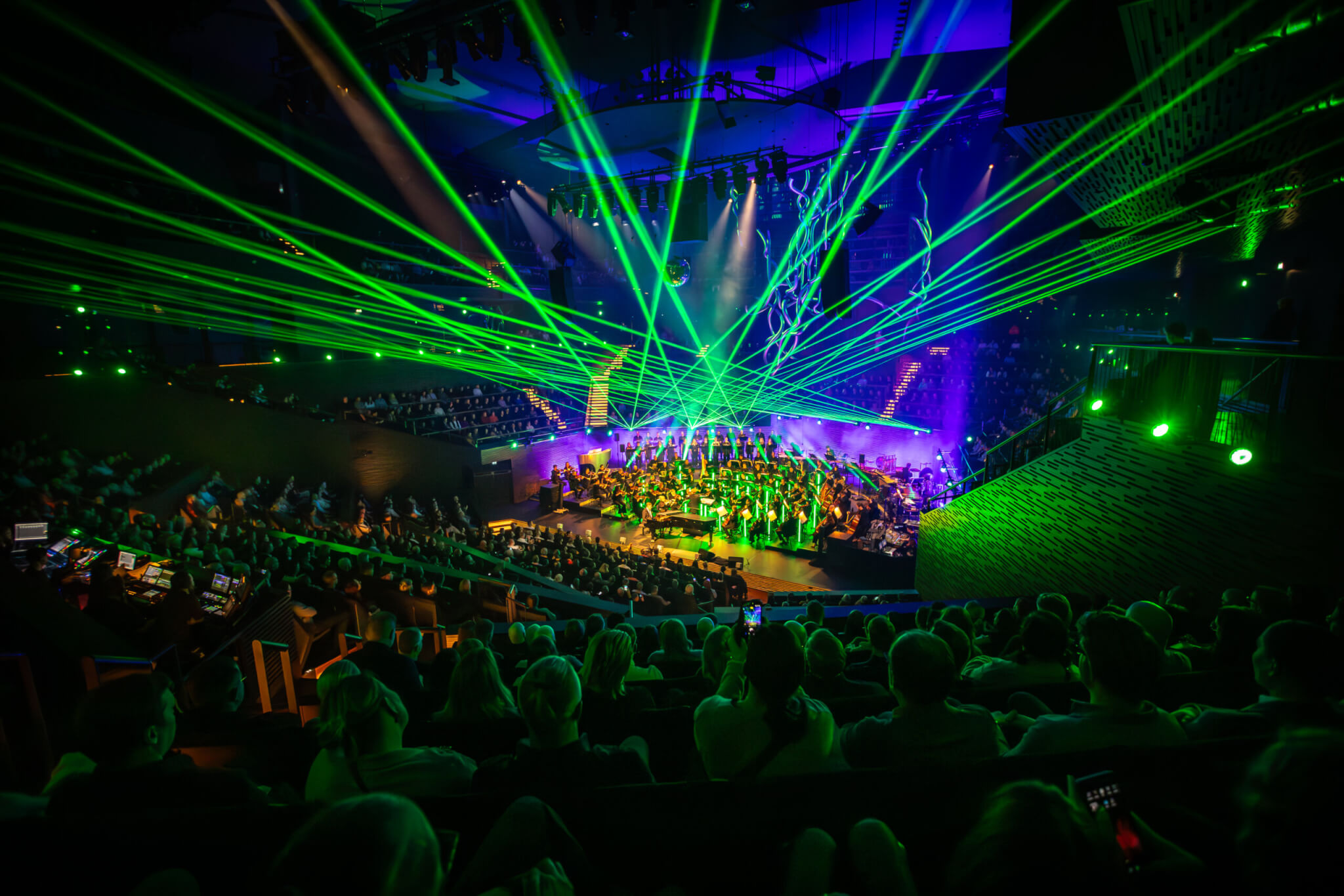 Musiikkitalon Konserttisali valaistuna vihreillä laservaloilla ja täynnä yleisöä.