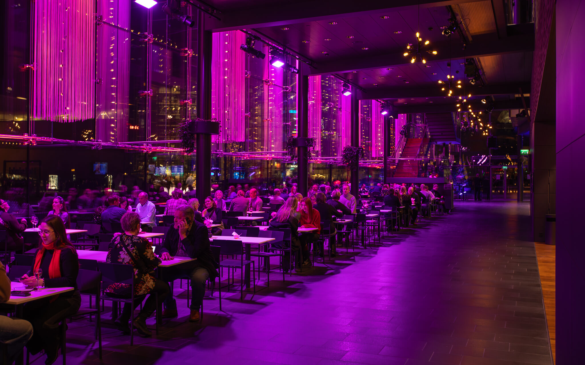 Ihmisiä Musiikkitalon Päälämpiössä. Yritystapahtumissa lämpiöt palvelevat ruokailu- ja messutiloina.