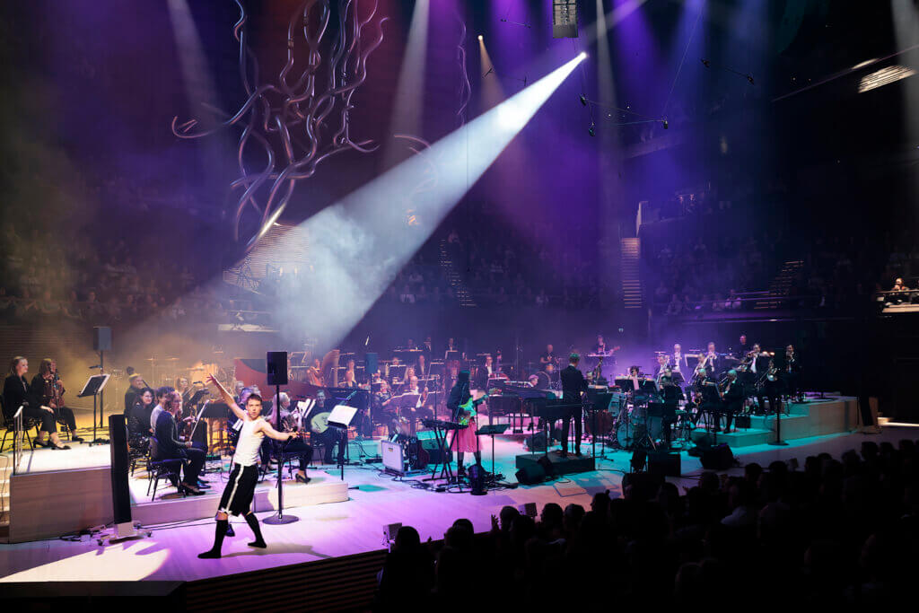 Musiikkitalon Konserttisalin lavalla orkesteri, sekä laulaja Olavi Uusivirta.