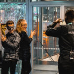 Pikkujoulujuhlijat poseeraavat kameralle Musiikkitalossa, ja järjestyksenvalvoja ottaa heistä valokuvan.