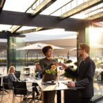 Ihmiset istuvat Musiikkitalon terassilla pöytien ääressä viinilasien kanssa auringonlaskun aikaan.