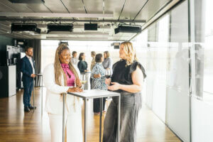 Ryhmä ihmisiä keskustelemassa ja seisomassa pystypöytien äärellä, Musiikkitalon Terassilämpiö kokoustilassa.